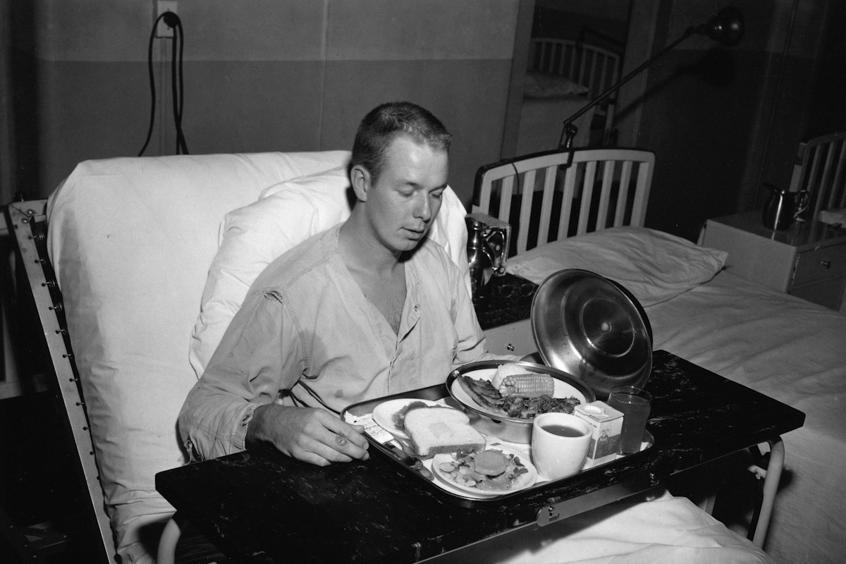 Paciente recibiendo su comida en una bandeja en la cama del hospital
